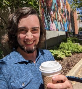 Aron Ryan, Elgin's third Poet Laureate, holding a cup of coffee